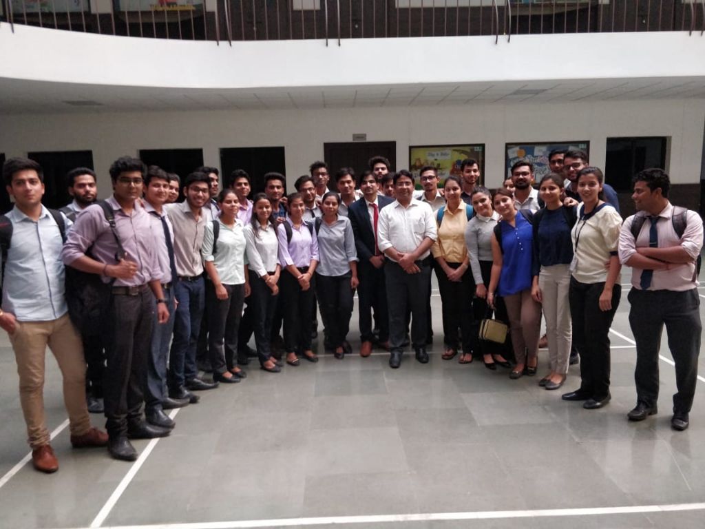 A large group of students and facilitators standing together in a school atrium