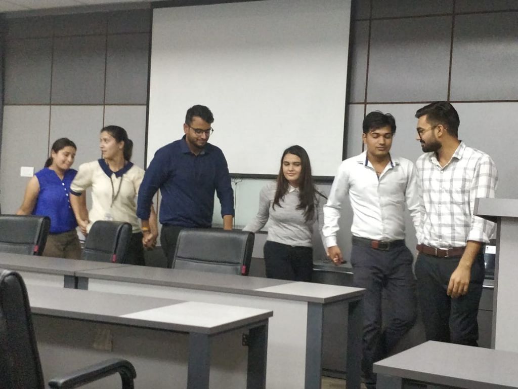 Students linked hand in hand walking across the front of a classroom