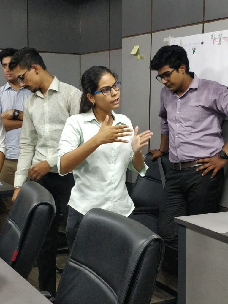A student in glasses explaining an idea with her hands to peers